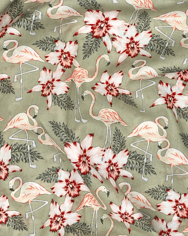 Close-up of sage green cotton fabric with pink flamingos and red hibiscus floral print, 58 inches wide.
