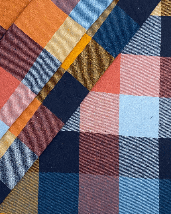 Folded yarn-dyed plaid flannel in navy, rust, mustard – soft brushed cotton.